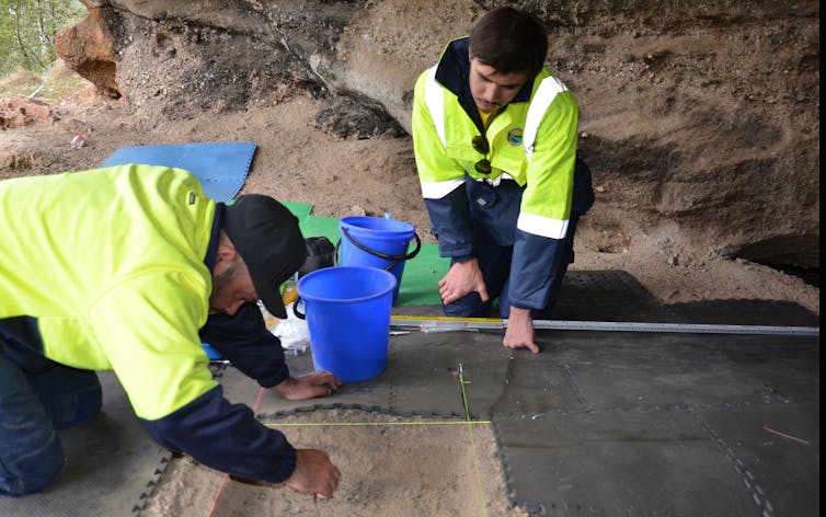 Two people excavating the ground of a rockshelter.