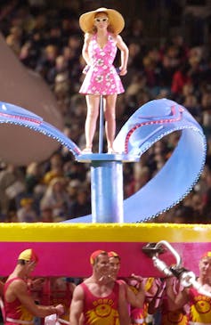 Woman stands on huge float, in shape of thong.