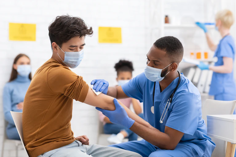 A nurse in a mask vaccinating a man in a mask