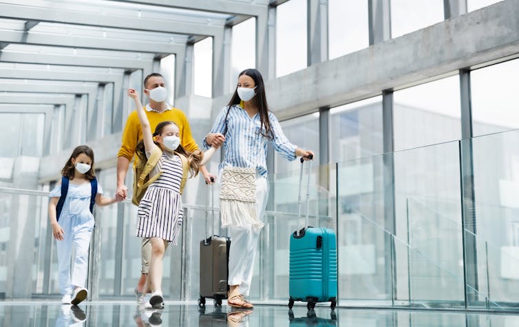 Une famille de quatre personnes portant des masques à l’aéroport
