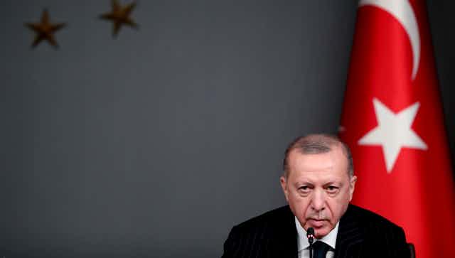 Turkish president Recep Tayyip Erdogan sits in front of a Turkish flag during a press conference  in Istanbul, October 2020