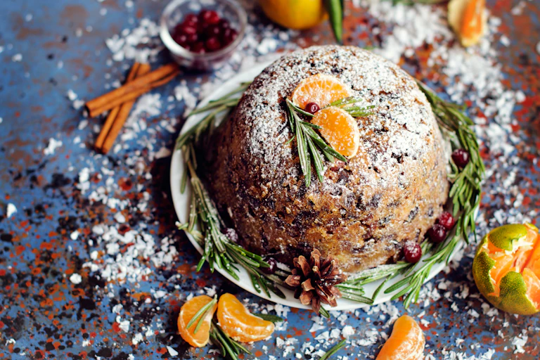 Christmas pudding with clementines and berries on blue background