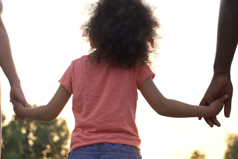 A child holds her parents hands.