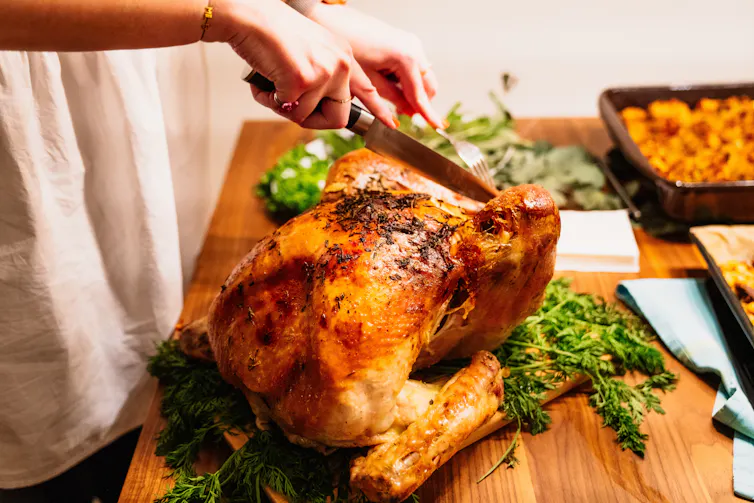 A woman carves a turkey.