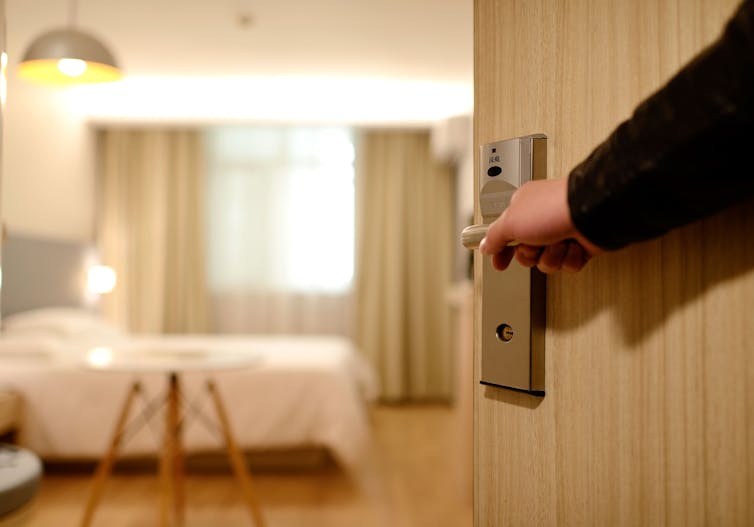 A porter opens the door into a brightly lit hotel room.