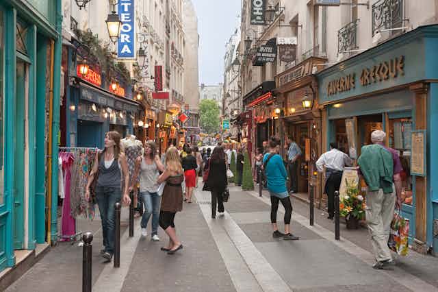 Calle peatonal con gente mirando escaparates del barrio latino de París.
