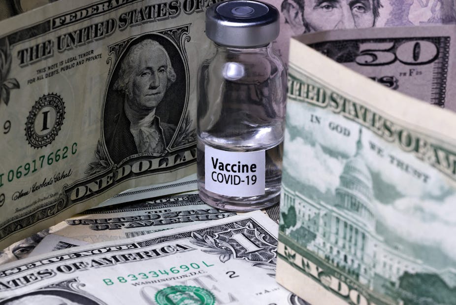 A vial of COVID-19 vaccine amidst a stack of cash.