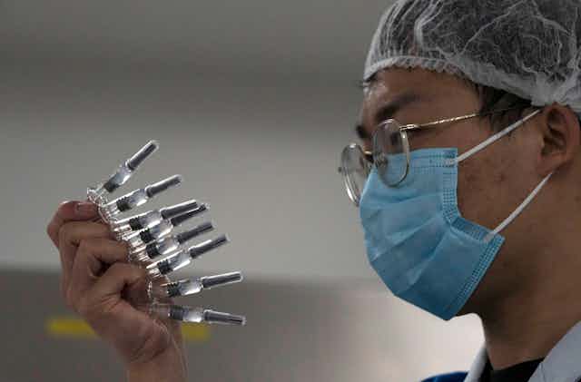 A man holding a number of syringes full of COVID-10 vaccine.