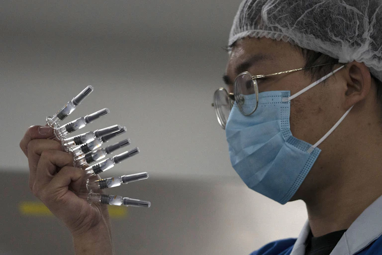 A man holding a number of syringes full of COVID-10 vaccine.