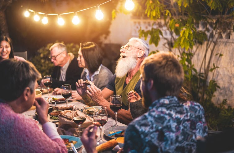 A group of people enjoy a festive evening meal outdoors.