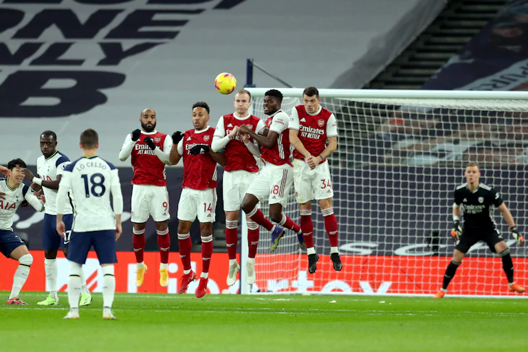 `Footballers defending a goal from a free kick.