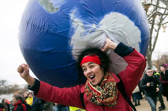 A protester carries an inflatable globe on her back.