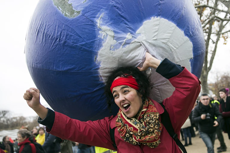 A protester carries an inflatable globe on her back.