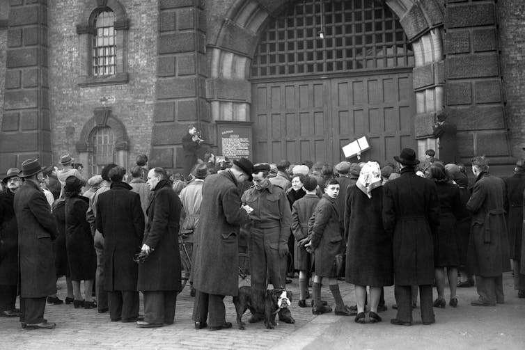 Group of people crowding in front of the gates of Wandsworth Prison in London in 1946.
