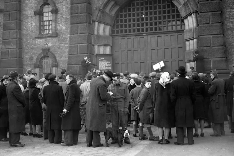 Group of people crowding in front of the gates of Wandsworth Prison in London in 1946.