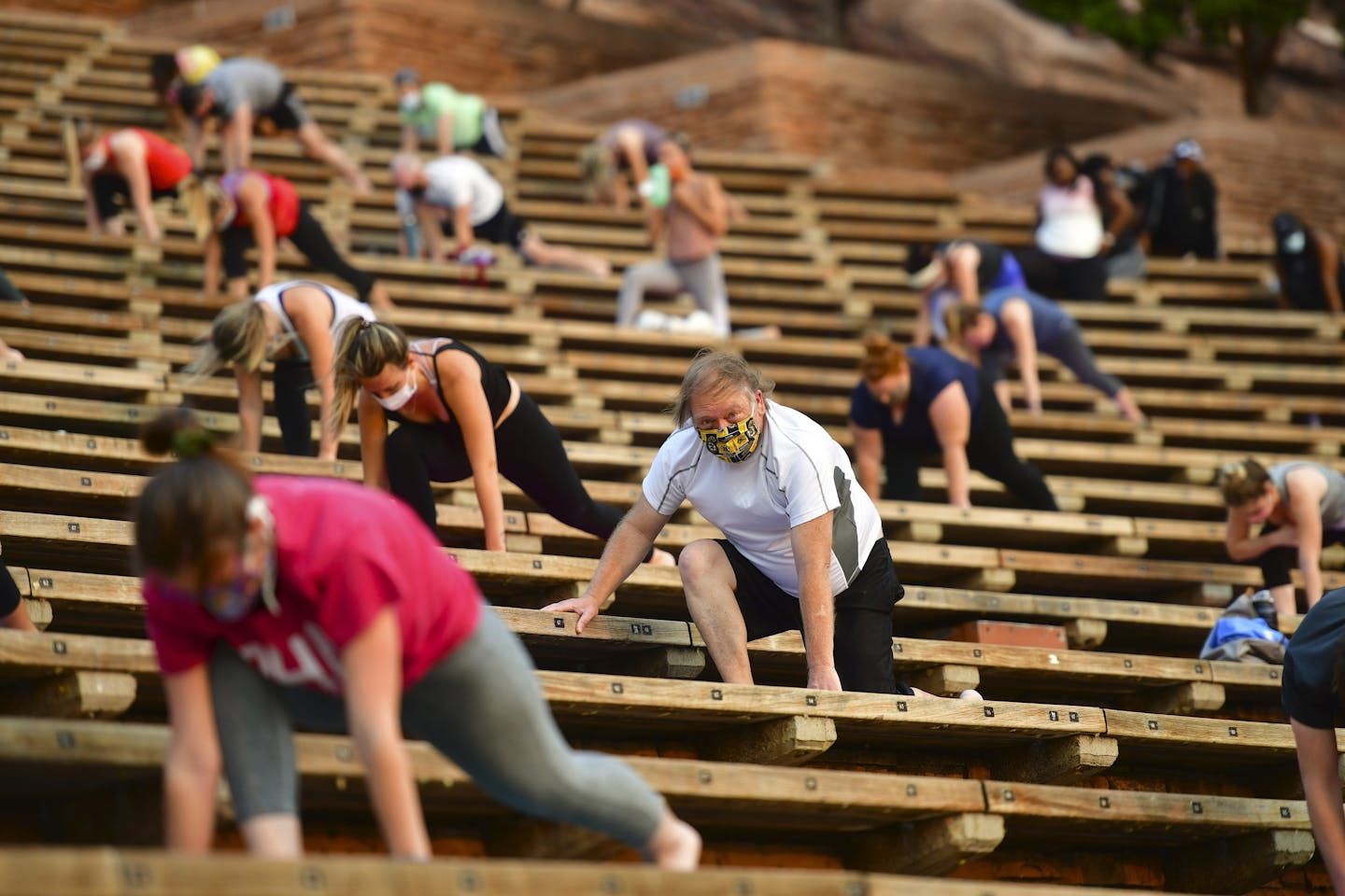people stretching while socially distanced in stadium seats