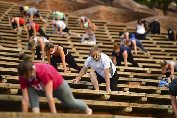 people stretching while socially distanced in stadium seats