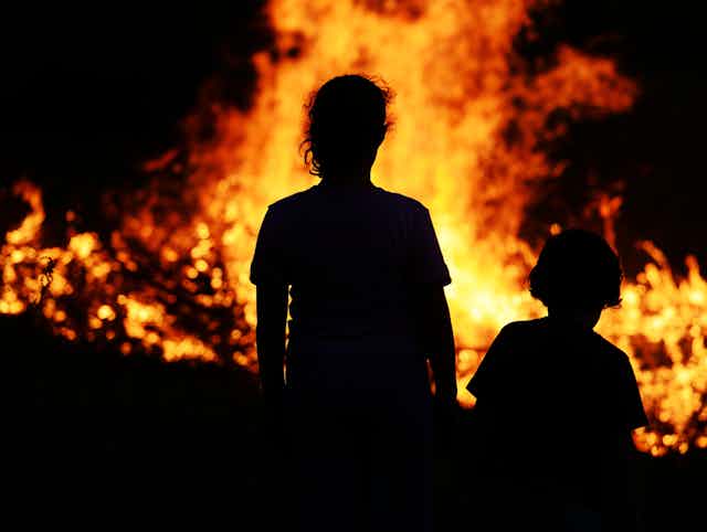 Woman and child standing in front of bushfire