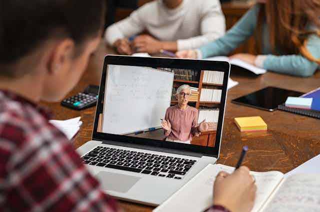 Student watching a video of a teacher on laptop