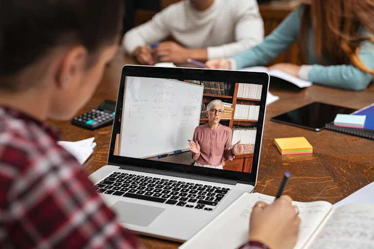Student watching a video of a teacher on laptop