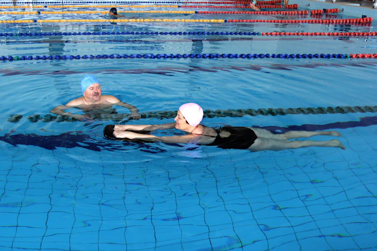 Middle aged couple swimming in an indoor pool.