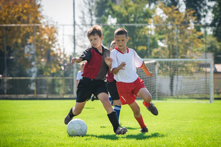 Dos niños se retan por el balón durante un partido de fútbol.