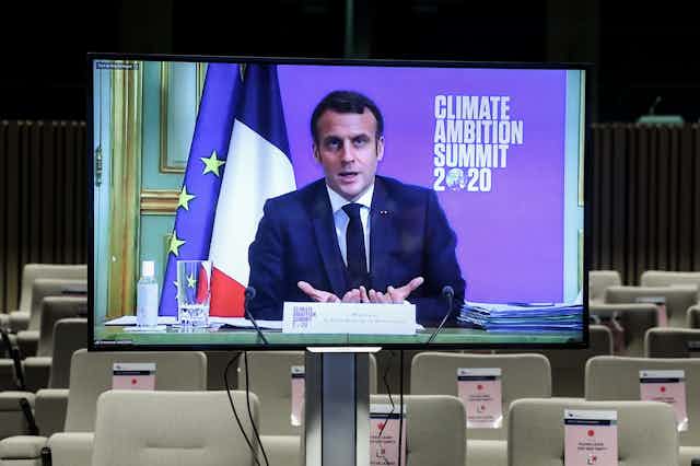 A TV screen broadcasts Emmanuel Macron's speech to a supposedly empty room.