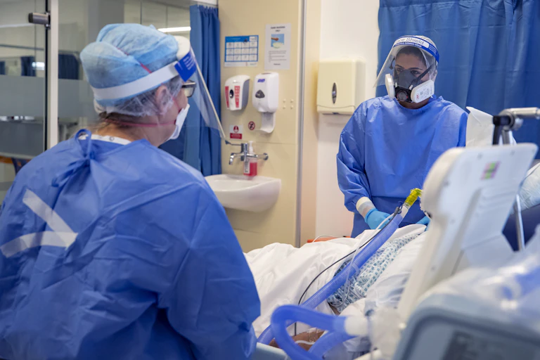 Two healthcare workers at bedside of a covid patient.
