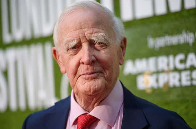Elderly man in a suit with a red tie.