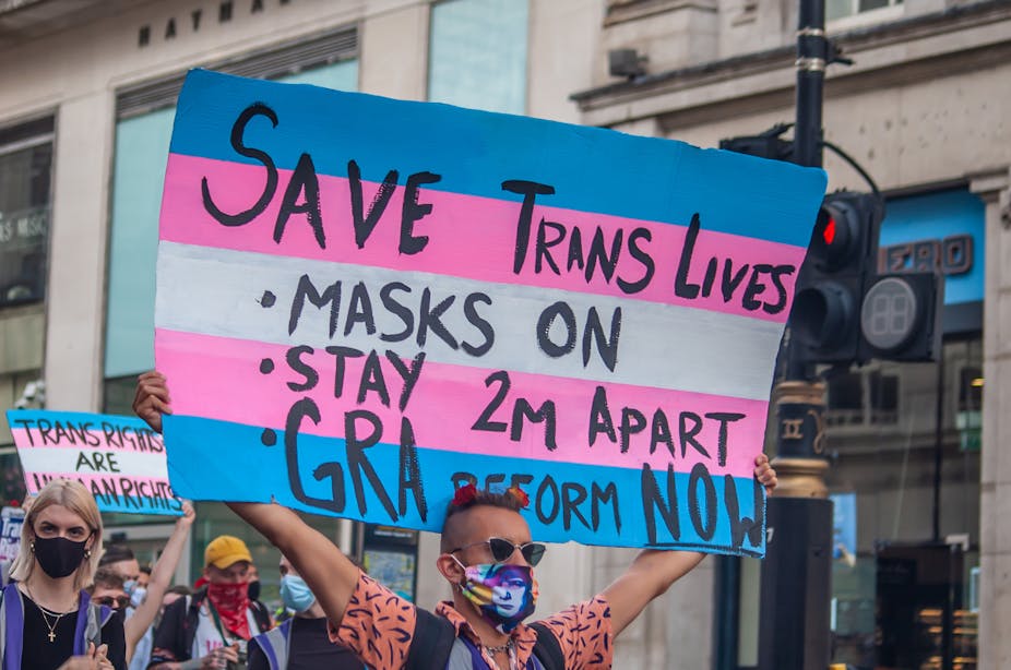 Protester holding a transgender flag sign encouraging social distancing at Trans Pride 2020 in London.