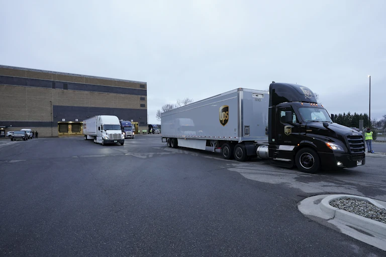 Two large trucks containing vaccines pulling away from the Pfizer building.
