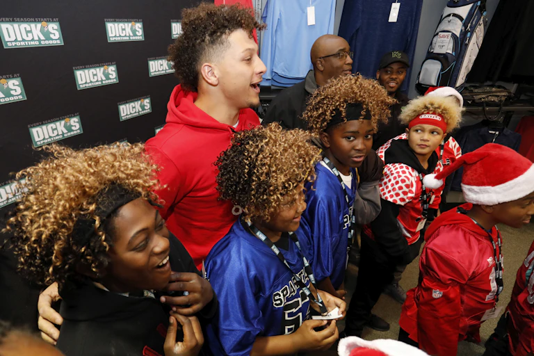 Man in red hoodie surrounded by happy children and Dick's logos