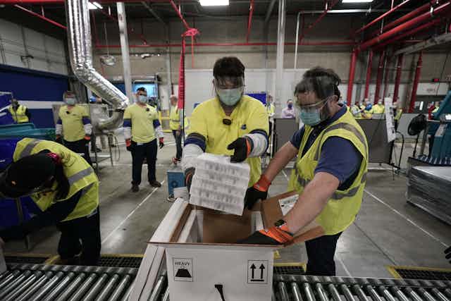 Two workers packing COVID-19 vaccine.