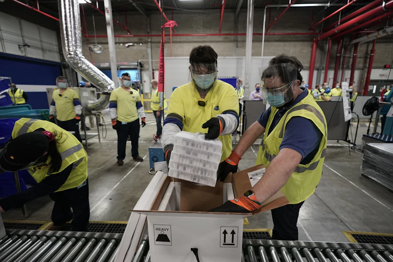 Two workers packing COVID-19 vaccine.