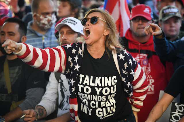 White woman in an American flag sweatshirt yells and points her finger