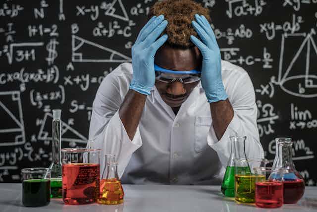 An African American male scientist is stressed out in a lab,