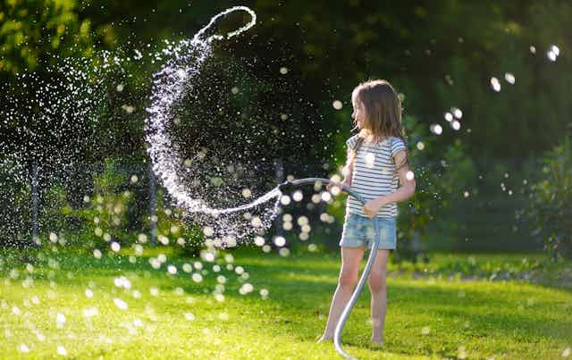 Girl playing with garden hose