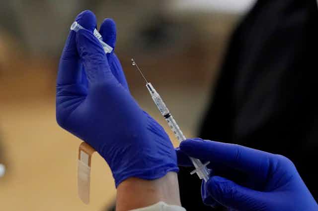 Gloved hands holding a syringe
