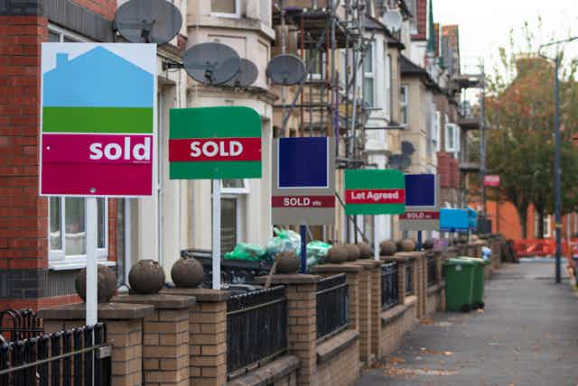 Several sold signs outside a row of houses on a street in the UK