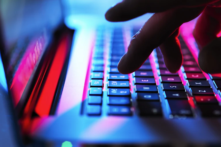 Image shows a closeup of fingers typing on a laptop.