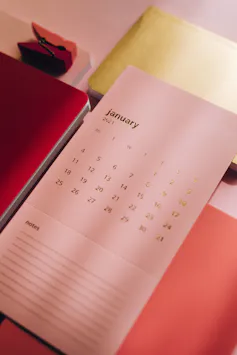 A calendar page for January with stationery on a desk top.