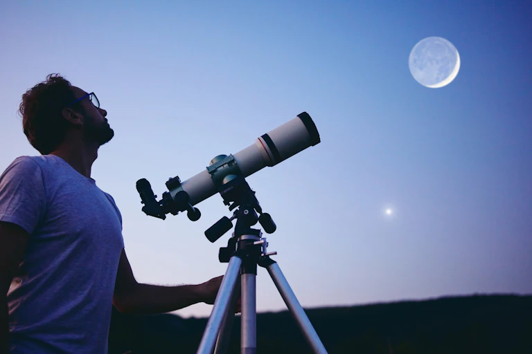 Man with telescope looks up to the sky.
