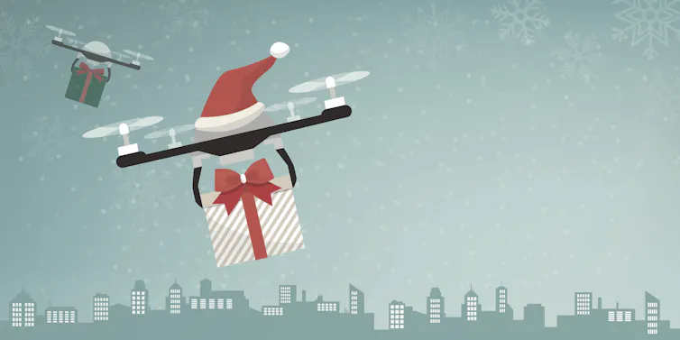 Illustration of two drones carrying gifts and decorated with Santa hats.