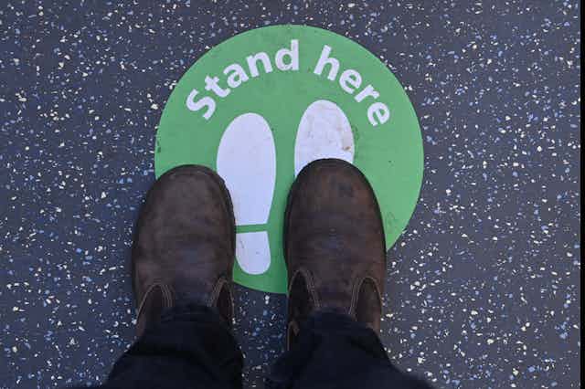 Feet almost (but not quite) standing on a sign marked 'stand here'
