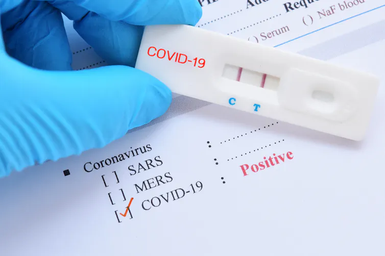 Hand in surgical glove holding a COVID-19 rapid test kit