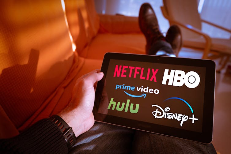 Person Holding Tablet With Netflix, Hbo, Prime Video, Hulu And Disney+ On The Screen