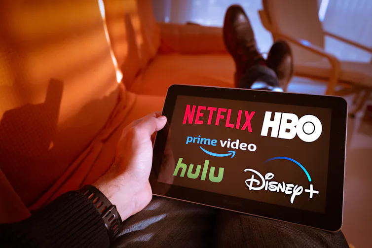 Person holding tablet with Netflix, HBO, Prime video, hulu and Disney+ on the screen
