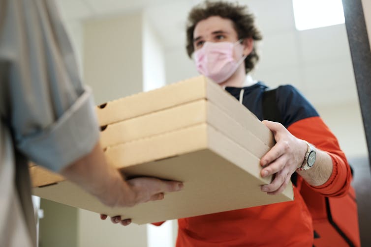 A man delivers pizzas to an apartment dweller.