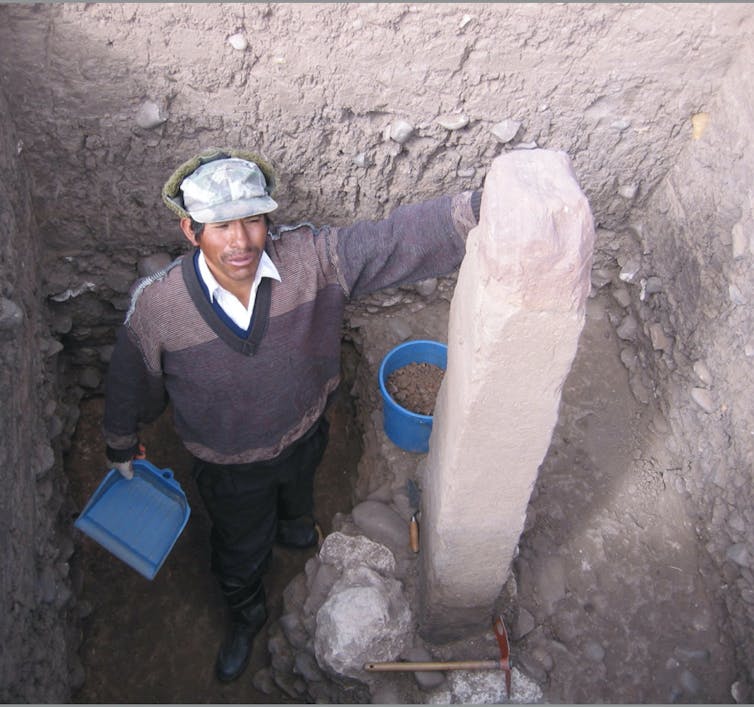 a man in a pit standing next to a monolith