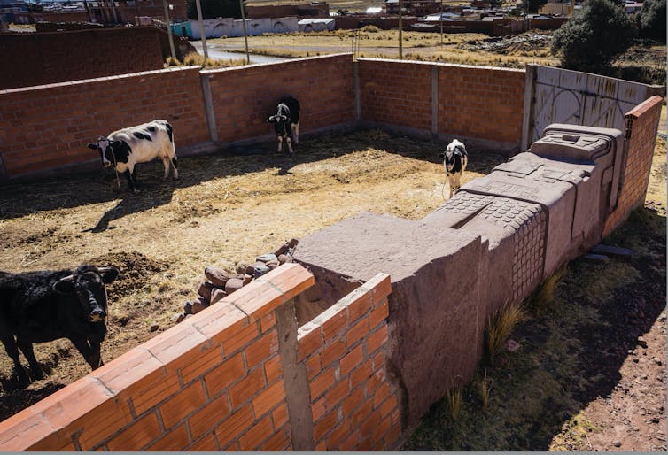 A carved monolith lies on its back and forms part of a wall.